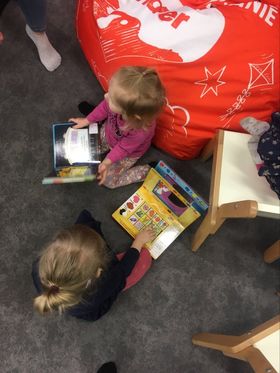 Dwoje dzieci siedzi na podłodze i ogląda książki