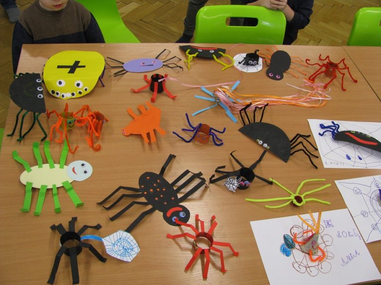 . Na stoliku leżą różnokolorowe, papierowe pająki wykonane przez uczestników zajęć.