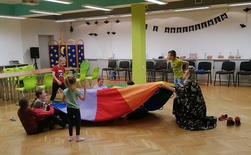 grupka dzieci uczestniczy w zabawie z wykorzystaniem chusty Klanza, którą prowadzi pani Dyrektor