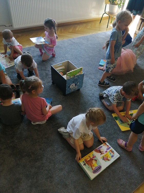 Dzieci siedzą na dywanie, przeglądają książki