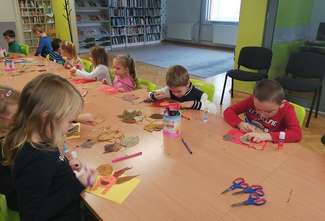 Przedszkolaki tworzą jesienne jeże, wykorzystując kolorowy papier i wysuszone liście