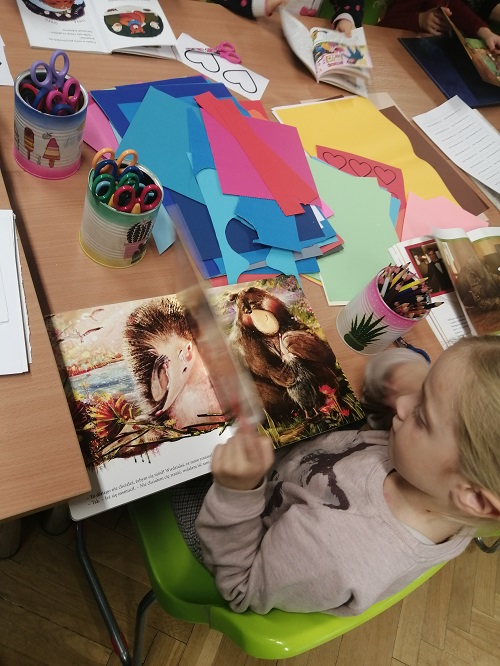dzieci przeglądają książeczki o misiowej tematyce przy stole, na którym leżą także materiały plastyczne