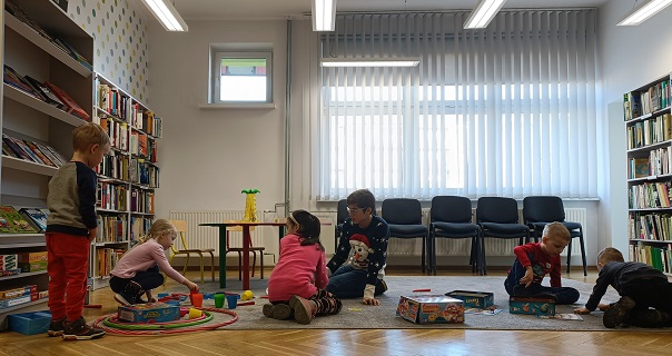 Grupa sześciorga dzieci bawi się na dywanie