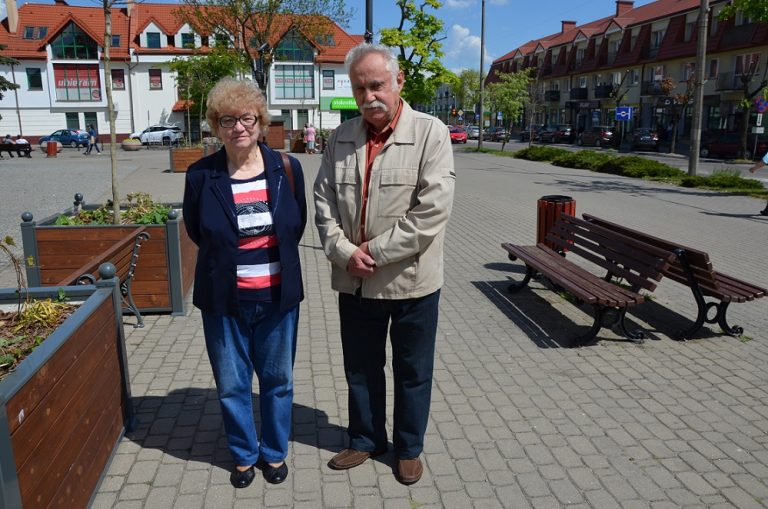 Starsze małżeństwo pozuje do zdjęcia na placu przed ratuszem