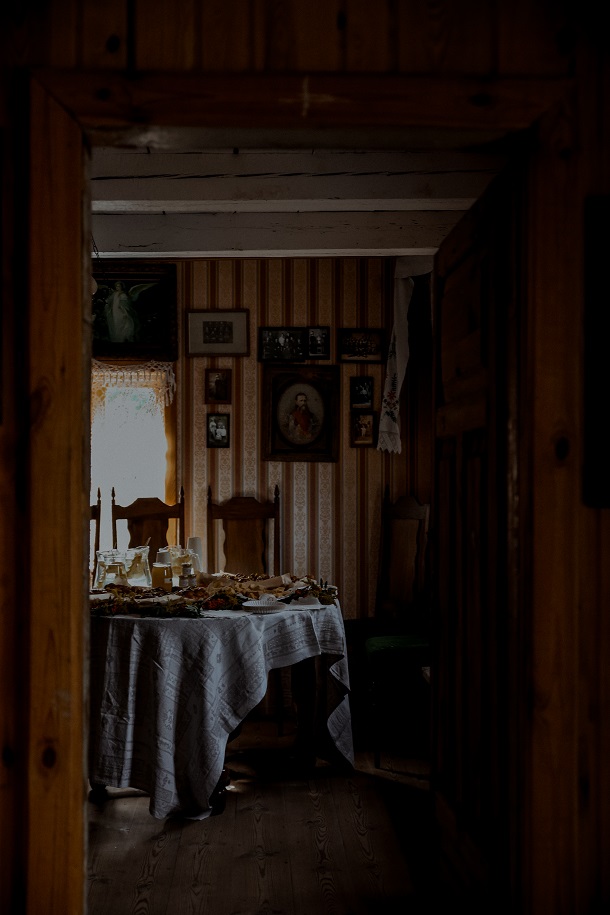 17. Widać wnętrze pokoju przez otwarte drzwi stojący nakryty bułkami i miodami stół
