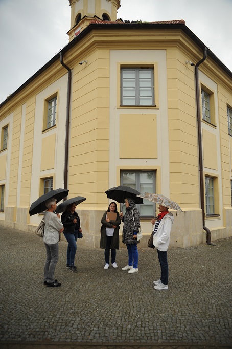 Pięć kobiet pod parasolami na brukowanym placu przez ratuszem w Bielsku Podlaskim