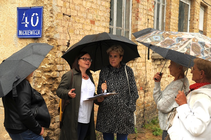 Pięć kobiet pod parasolami przed ceglanym budynkiem dawnej piekarni nr 1 przy ulicy Adama Mickiewicza. Na ścianie tabliczka z adresem: Mickiewicza 40.