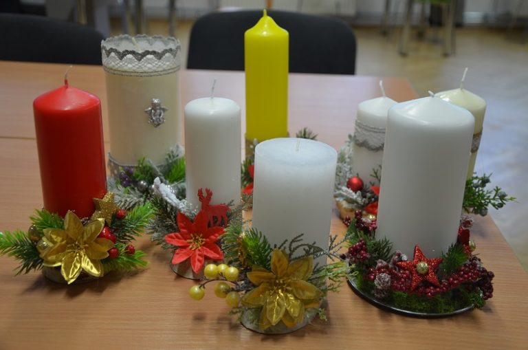 Na stole siedem stroików świątecznych w formie ozdobionych świec