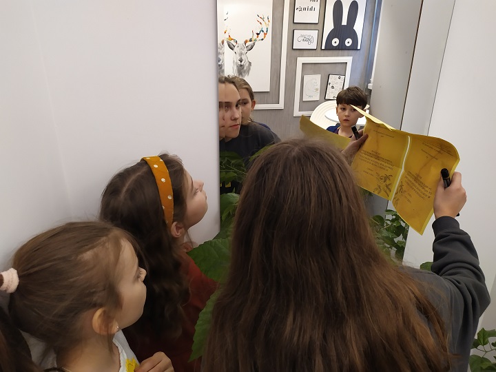 Trzy dziewczynki i chłopiec w trakcie rozszyfrowywania zagadki przy użyciu lustra